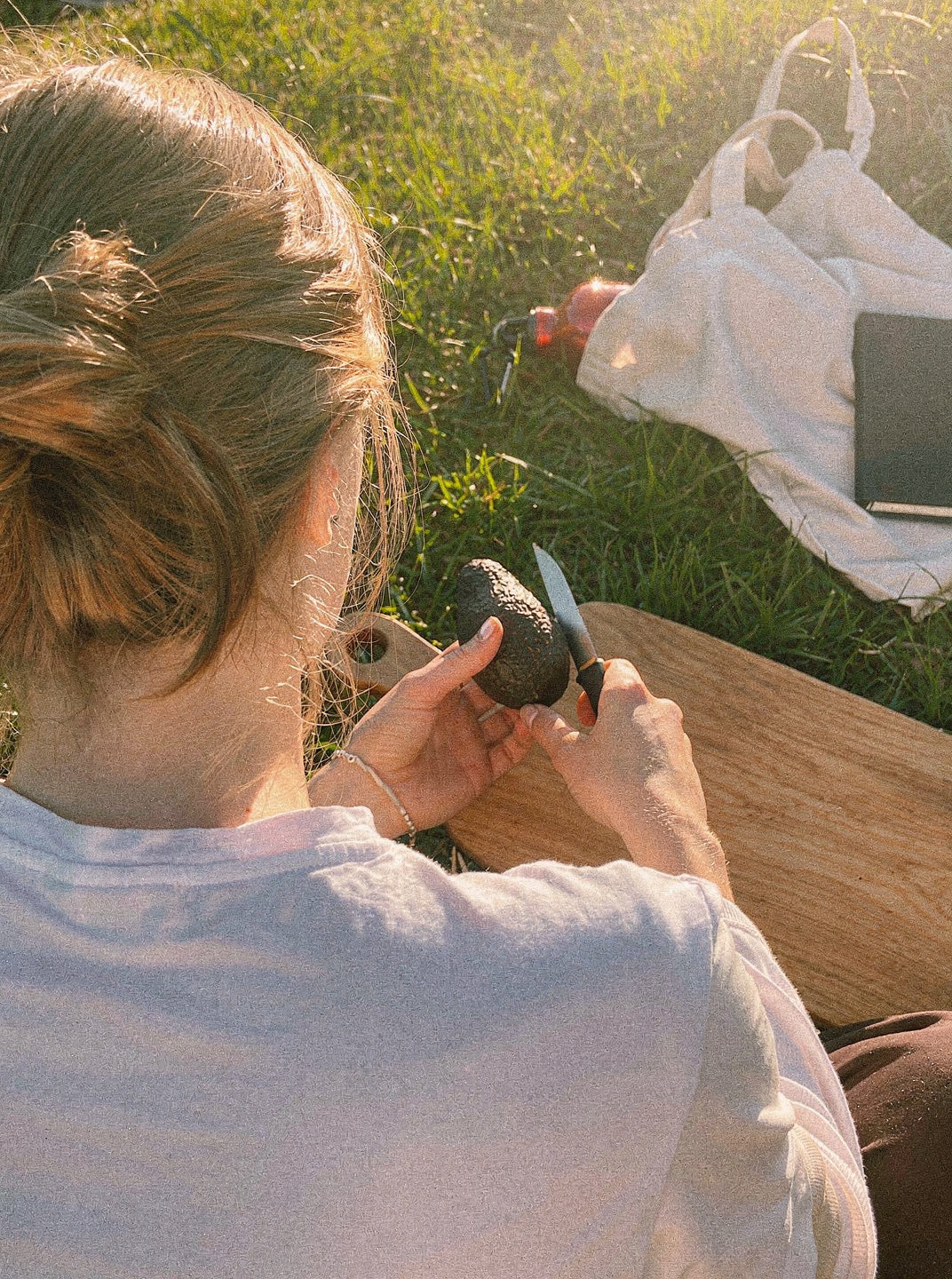 Frau packt beim Picknick im Gras eine Thermoskanne aus, Bruno Servierbrett liegt daneben.
